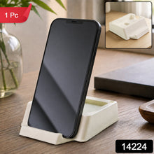 A black smartphone stands vertically in a cream plastic holder on a wooden table, with a red 