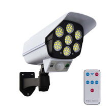 White dummy security camera with seven LED lights and a remote control on a white background.