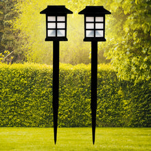 A pair of sleek black solar garden lights illuminating a lush green lawn at dusk.