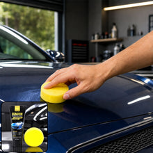 A hand applies yellow foam applicator with scratch removal wax to a blue car hood.