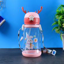 A pink and clear water bottle with a bunny design, deer antlers, and a colorful strap, against a background.