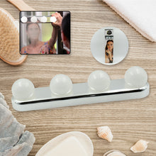 A white LED vanity light with four round bulbs is displayed on a wooden surface with bath accessories and product – view 3