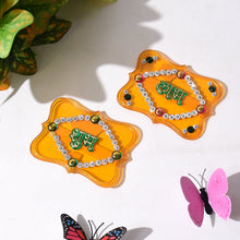 Two ornate yellow Shubh Labh wall hangings with green text and clear and colored jewels.