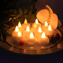 Twelve white LED floating candles with warm yellow flames on a decorative plate with a white orchid and green leaves.