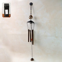 Metal wind chime with Om symbol hanging outdoors in a garden