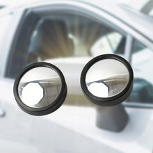 Two round black blind spot mirrors shown against a blurred white car background.