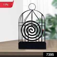 Iron birdcage mosquito coil holder placed on a rustic wooden table.