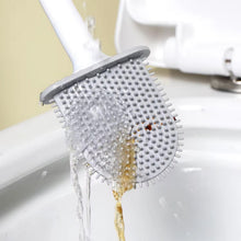 Water streams over the gray silicone bristles of a toilet brush, rinsing away brown residue into a white toilet.