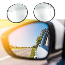 A car's side mirror reflecting a sunny road, with two blind spot mirrors in the foreground.