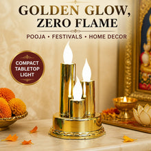 A golden triple LED flameless candle lamp on a marble surface, surrounded by orange flowers and a golden bowl.