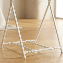Close-up view of the white plastic base and connecting pieces of the bag holder on wood flooring.