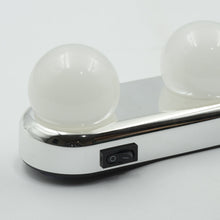 A close-up of the white LED vanity light shows two round bulbs and a black on/off switch on the chrome base.