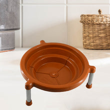 Orange plastic stand with three silver legs on a white countertop, with a woven basket in the background.