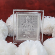 Silver-plated Ganesha idol in an acrylic frame, surrounded by several white fluffy decorations on a red background.