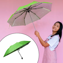 A smiling woman holds an open green and silver umbrella against a pink background, with a folded umbrella in an inset.