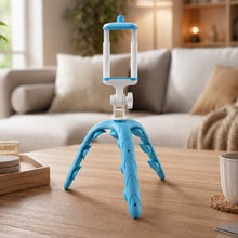 A blue and white flexible tripod for phones standing on a wooden coffee table in a modern living room setting.