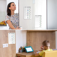A woman opening a refrigerator with two 'MY CHORES' boards on it, and a child studying at a desk with another board on the