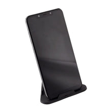 A black smartphone stands vertically on a black pyramid-shaped mobile stand against a white background.