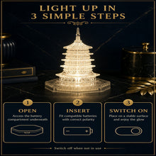 An illuminated LED crystal pagoda light on a dark surface with instructions for opening, inserting batteries, and switching