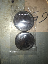 Two round blind spot mirrors in a clear plastic bag on a dark, scratched surface.