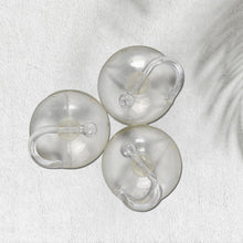 Two transparent suction hooks with strong hold on a bathroom tile wall.