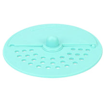 A light green silicone drain strainer with a central knob and two sections of holes is shown from above.