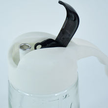 Pouring olive oil using glass oil bottle dispenser in kitchen setting