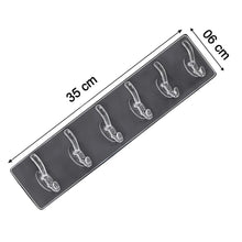 Elegant golden and transparent 6-pin hooks providing storage on a bathroom wall.