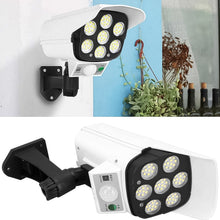 Two views of the white dummy security camera with seven LED lights, one mounted on a wall and another angled view.