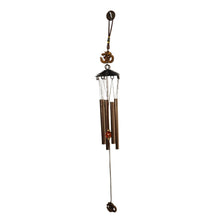 Side view of metal wind chime with Om symbol against green background