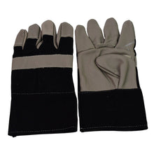 Pair of robust gardening gloves lying on garden soil with tools.