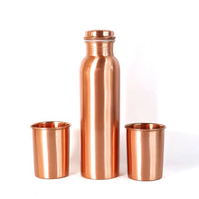 A person pouring water from the leakproof copper bottle into one of the matching glasses.