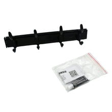 Black four-hook coat rack and a clear plastic bag containing adhesive and instructions on a white background.
