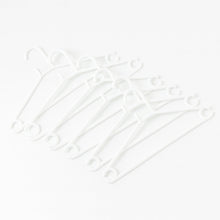 Stack of 6 white plastic clothes hangers ready for use