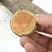 A hand holds a freshly cut, round piece of wood, showing its concentric rings.