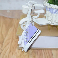 Mini shoe keychain attached to a black backpack, showcasing its size.