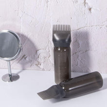 Plastic hair oil applicator bottle with a built-in comb brush for easy dispensing.