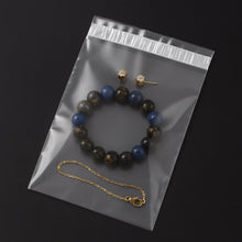 A clear polybag containing a blue and black beaded bracelet, a gold chain bracelet, and two small gold stud earrings.