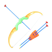 An Indian child joyfully aiming the toy bow and arrow set at a target board outdoors.