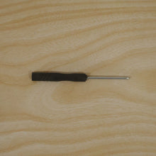 A black and silver mini screwdriver is centered on a light wooden surface.