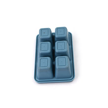 Hands gently bending the flexible blue silicone ice tray to release ice cubes.