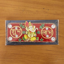 A red rectangular Ganesha Shubh Labh wall decor with white and green embellishments, sealed in clear plastic packaging.