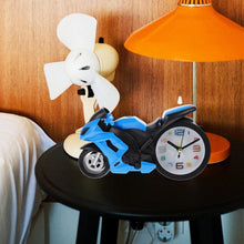 The unique bike engine style clock on a clean white desk next to a pen, showing its suitability for office spaces.