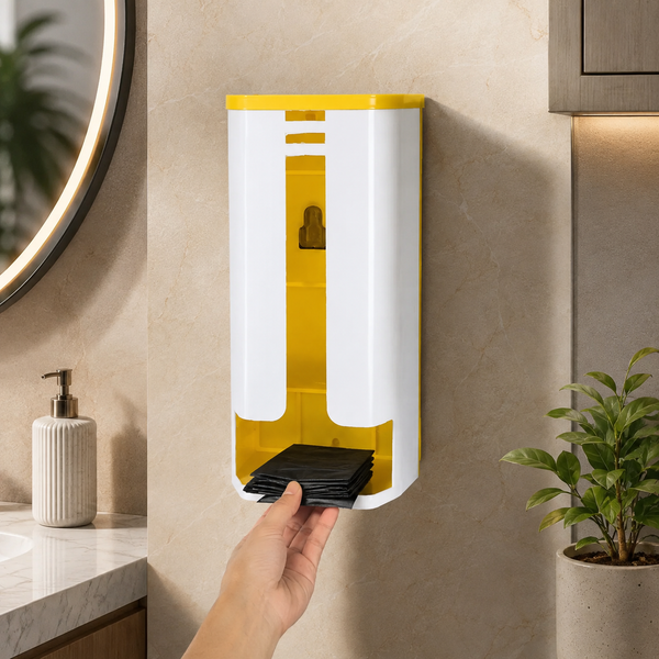 A hand pulls black plastic bags from a white and yellow wall-mounted dispenser in a bathroom setting.