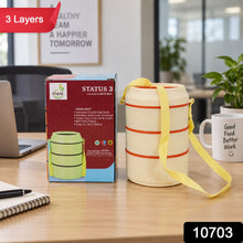 The cream-colored three-layer lunch box and its packaging are shown on a desk, with a red 