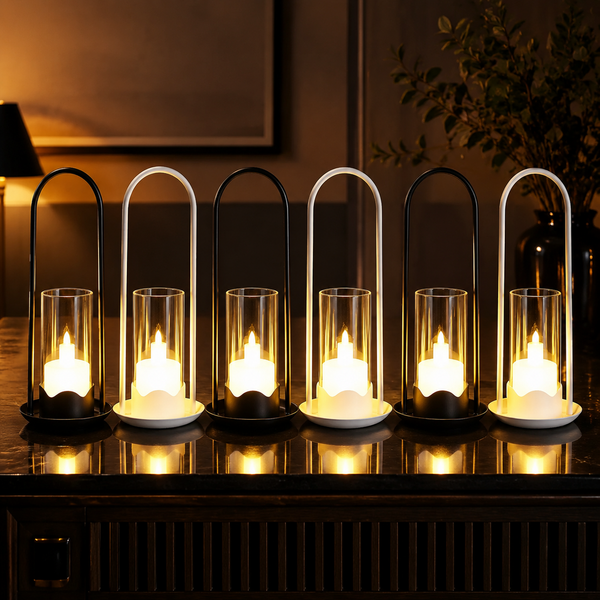 Six flameless LED lanterns with glass cylinders and arched metal handles, three black and three white, glowing warmly on a