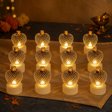 Twelve gold mesh LED tealights glowing on a decorative table runner with flowers and a brass oil lamp in the background.