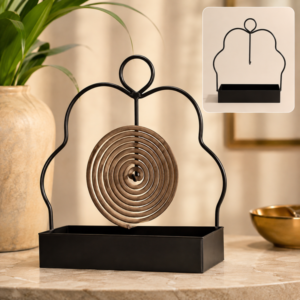 A black metal mosquito coil holder with a brown spiral coil sits on a marble surface next to a plant.
