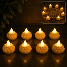 Eight illuminated lotus-shaped LED tealight candles arranged on a dark surface with a plant in the background.