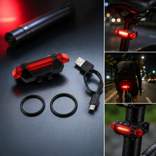 A red LED bicycle tail light, USB cable, and two rubber rings are displayed on a dark surface. The light is illuminated.